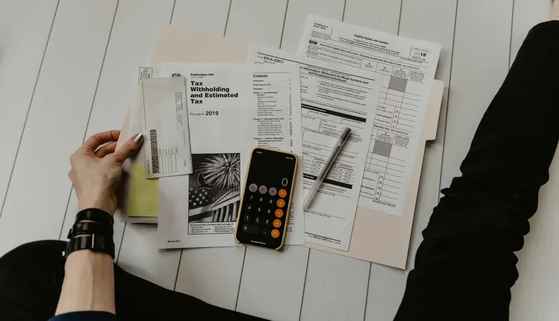 Person reviewing finances with a calculator and documents