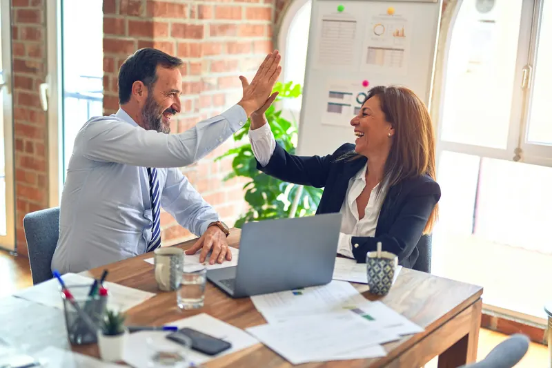 Two colleagues celebrating a win at their desk